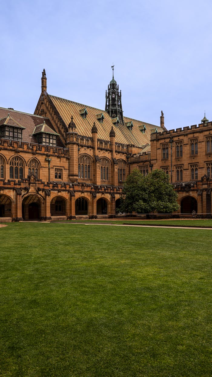 services-02 The iconic sandstone architecture of the University of Sydney Quadrangle on a clear day, a symbol of academic excellence.